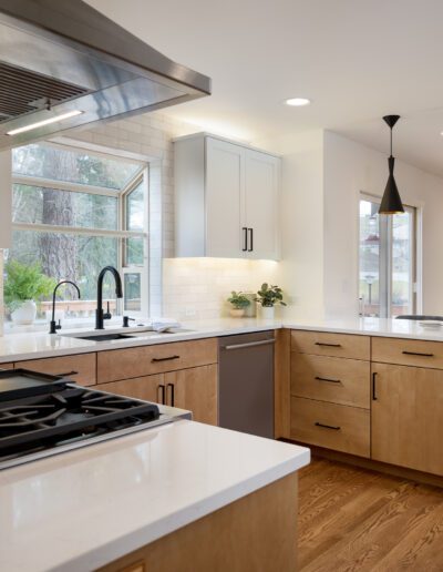 A kitchen with white cabinets and wood floors.