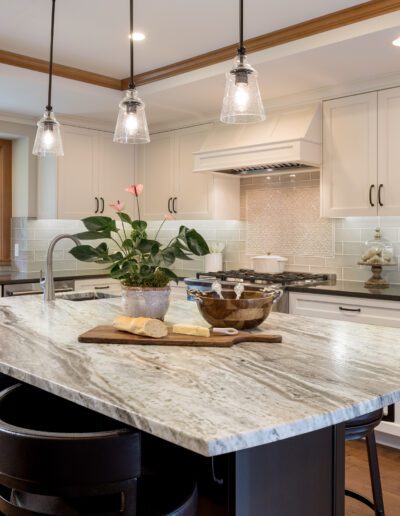 A kitchen with a marble counter top and black cabinets.