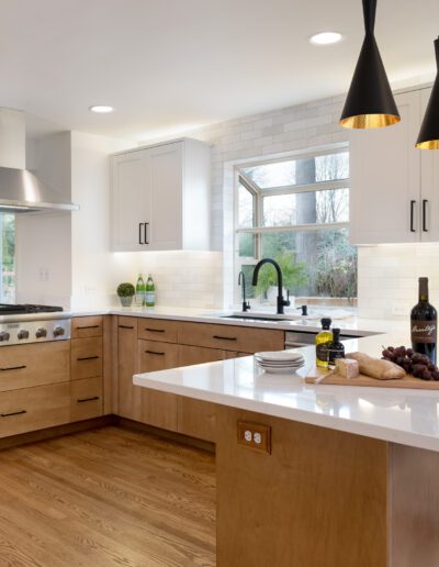 A modern kitchen with white cabinets and wood floors.