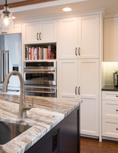 A kitchen with white cabinets and marble counter tops.