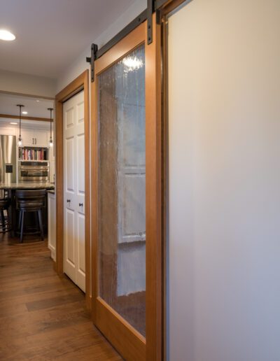 A hallway with wood floors and a sliding barn door.