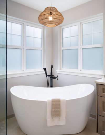 A white bathtub in a bathroom with large windows.