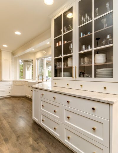 A kitchen with white cabinets and hardwood floors.