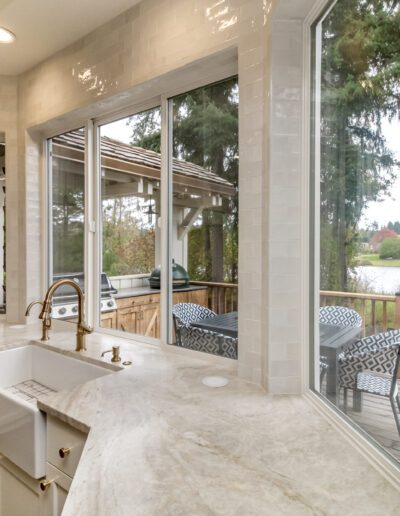 A kitchen with a large window overlooking a lake.