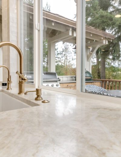 A kitchen with a large window overlooking a wooded area.