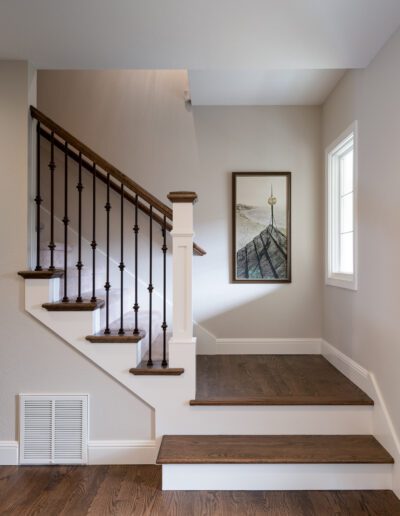 A staircase in a home with hardwood floors and a painting.