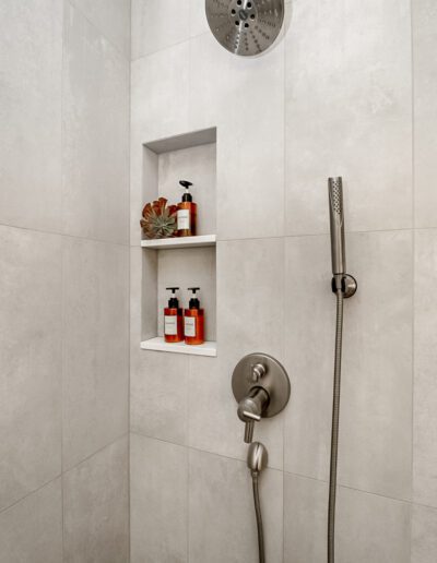 A bathroom with a shower head and shelves.