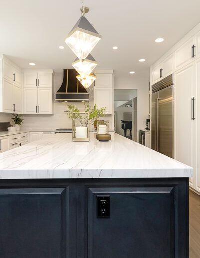 A kitchen with white cabinets and a marble island.