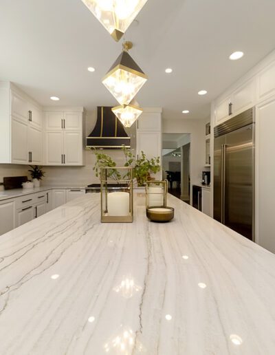 A white kitchen with a marble counter top.