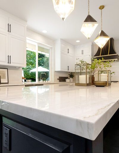 A kitchen with a marble counter top and black stools.