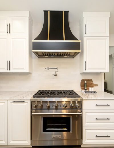 A white kitchen with a black stove hood.