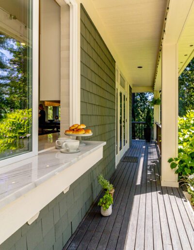 A porch with a table and chairs and a view of a wooded area.