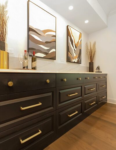 A black and gold kitchen with wooden floors.