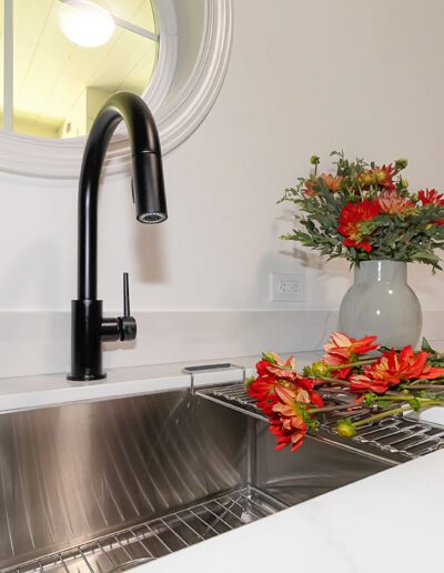 A kitchen sink with flowers in it.