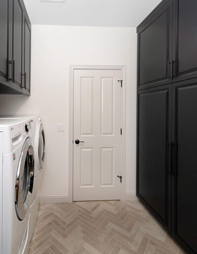 A laundry room with black cabinets and a washer and dryer.